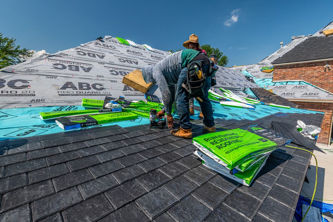 Workers installing a synthetic slate roof on a brick house