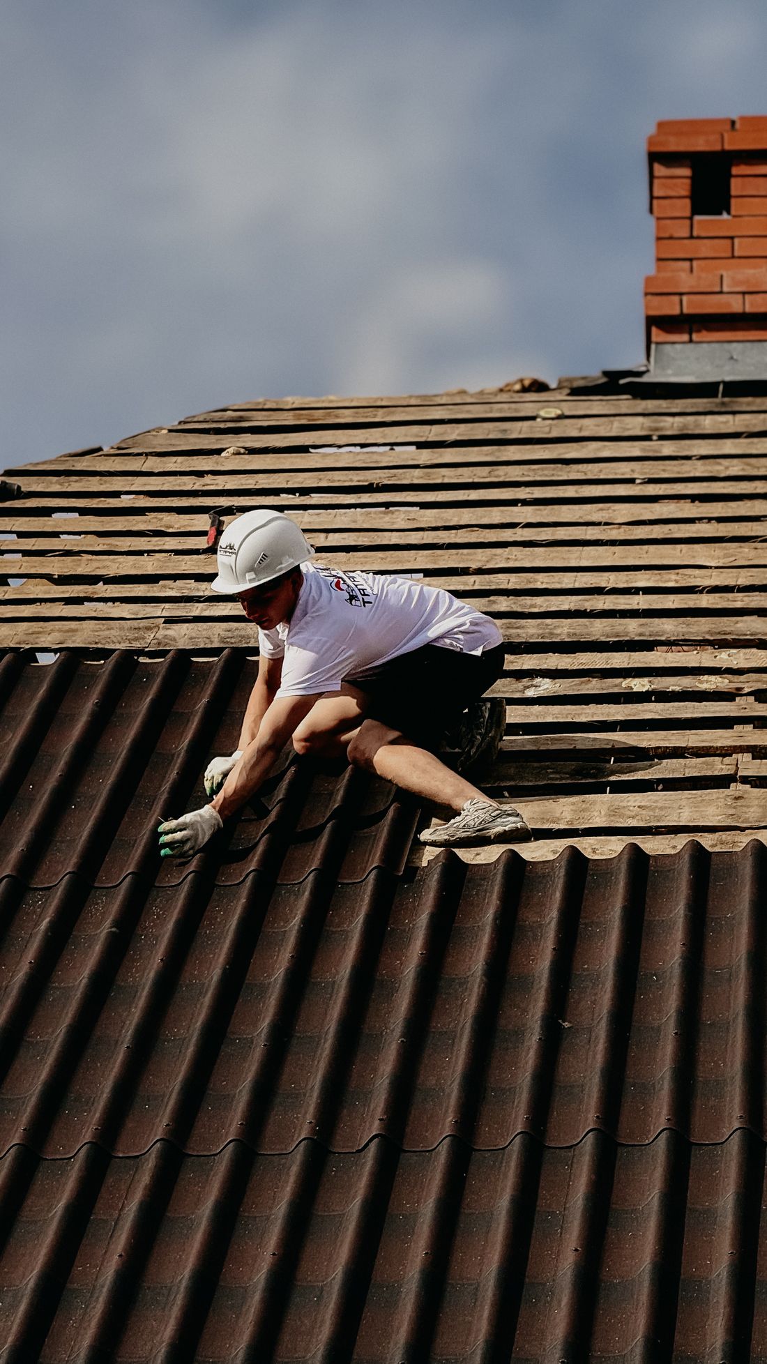 Roofer installing tiles on a sloped residential roof
