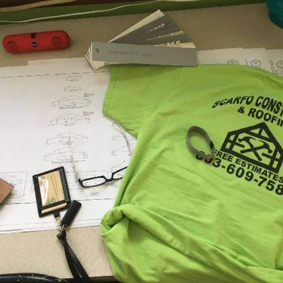 Scarfo Construction and Roofing branded shirt with blueprints and plans on a desk